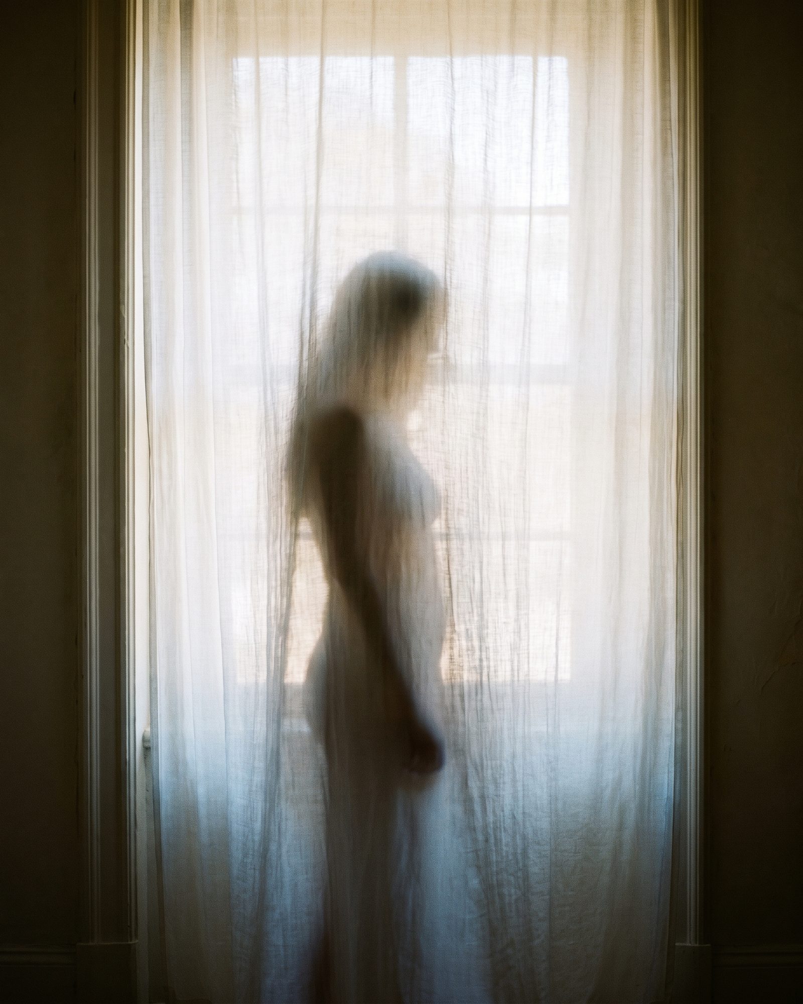 A silhouette behind a sheer curtain
