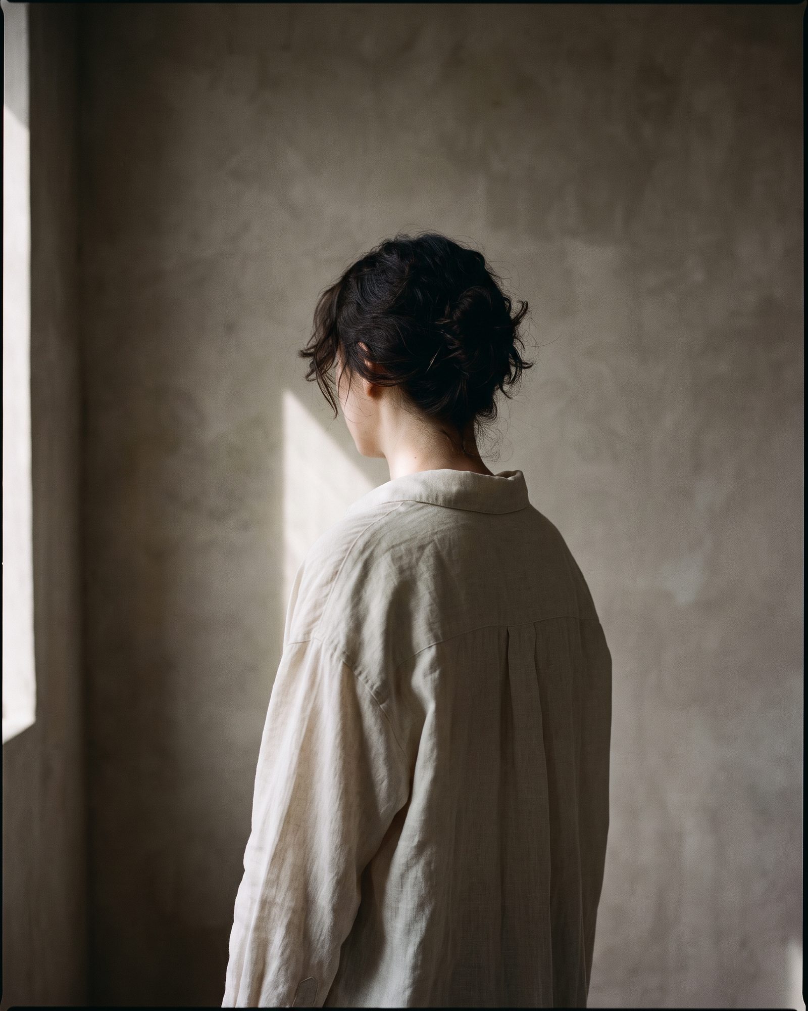 Portrait from behind against a plaster wall