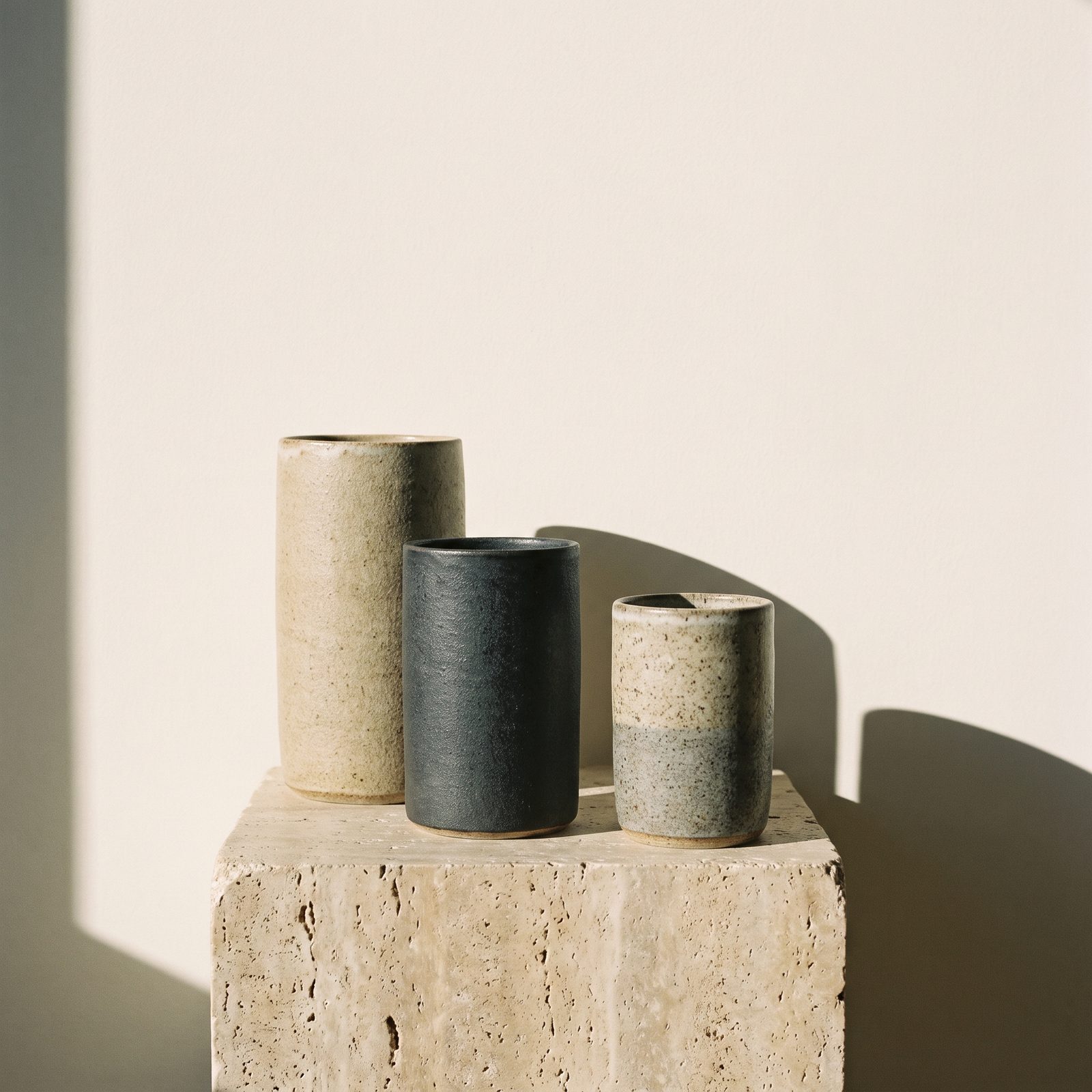 Three stoneware vessels on a travertine plinth